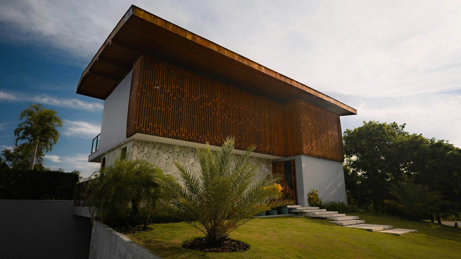 Maison contemporaine bois et pierre ouverte sur une pelouse
