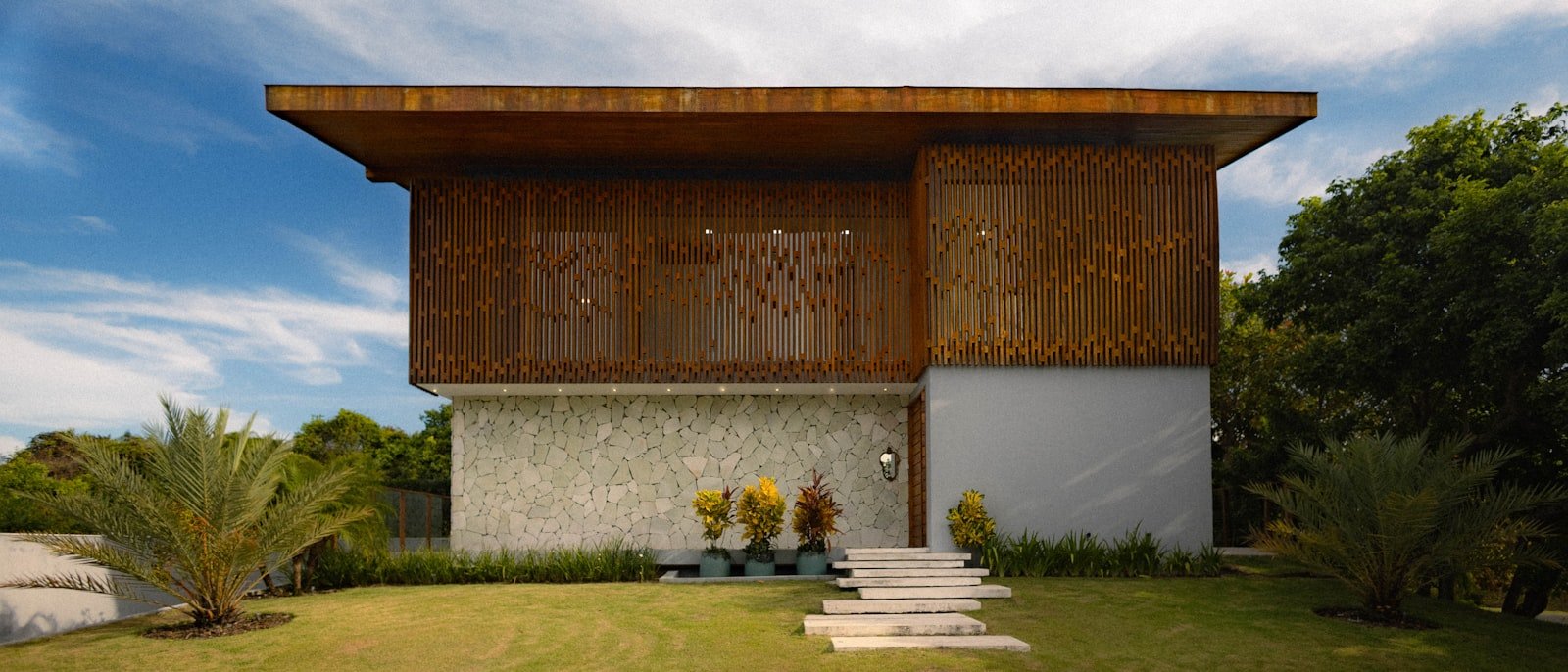 Façade en bois et pierre d'une maison contemporaine vue depuis le jardin