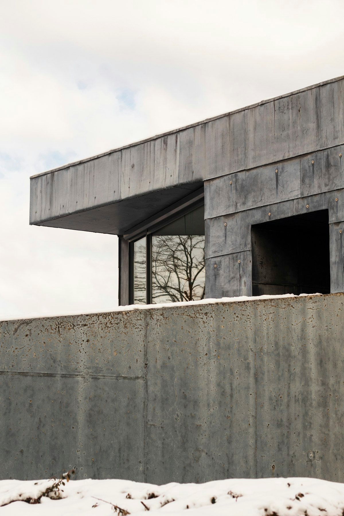 Volume en béton en porte-à-faux au-dessus d'un mur de clôture